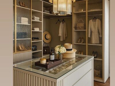 Dressing la comandă de lux cu insulă centrală cu blat din sticlă, rafturi cu ramă aurie și candelabru elegant