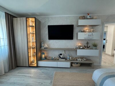 Mobilă living la comandă din lemn deschis cu vitrină iluminată, rafturi flotante albe și comodă TV cu sertare