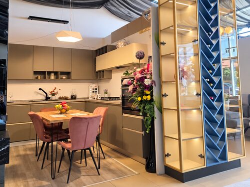 Bucătărie bej în L, cu masă de dining, în showroomul Kera